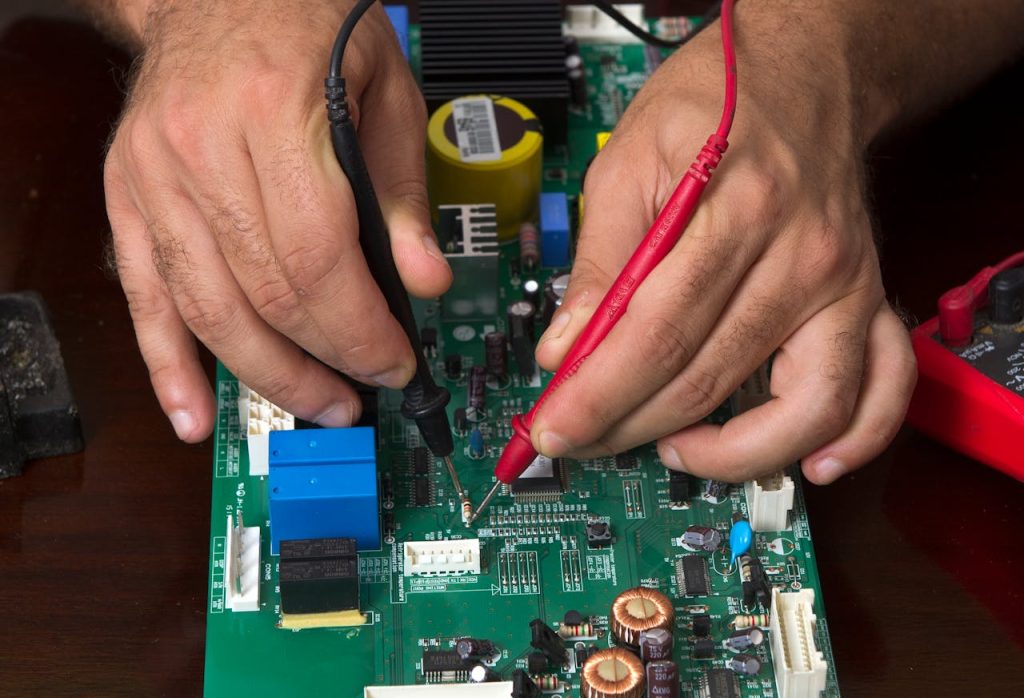 man-hands-working-on-computer-motherboard-10699353 A detailed view of hands working on a circuit board using probes, depicting precision and electronics repair.